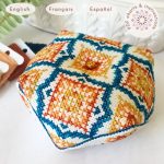 Patrón de punto de cruz Biscornú Azulejos Sevillanos. Alfiletero octogonal bordado con motivos geométricos inspirados en los azulejos de fabricación sevillana en azul y naranja. Texto indicando que es un producto digital disponible en español, inglés y francés.