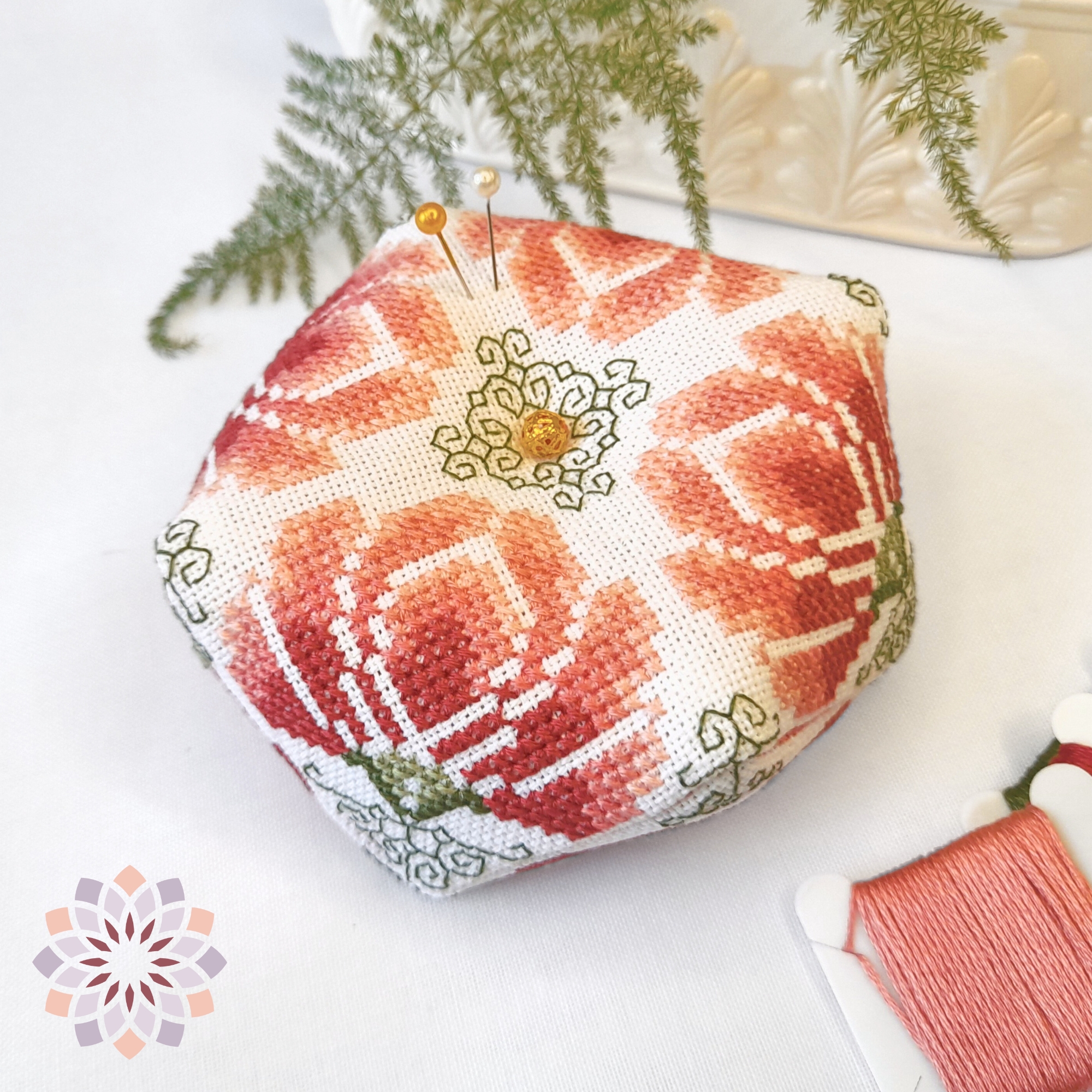 Begonias-Biscornu-Cross-stitch-Pattern-No-badge Octagonal embroidered biscornu pin cushion with four geometrical begonias in warm hues of pink. Embroidered in cross and back stitches. Text overlay indicating it is a digital product.